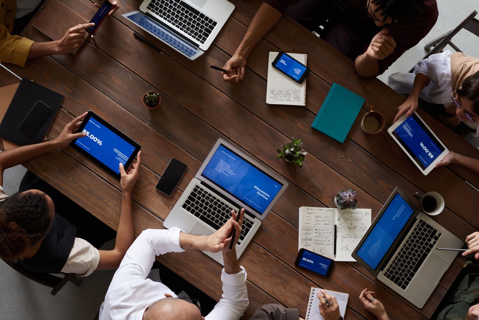A team reviewing analytics on tablets and laptops around a table, representing CRM and follow-up operations