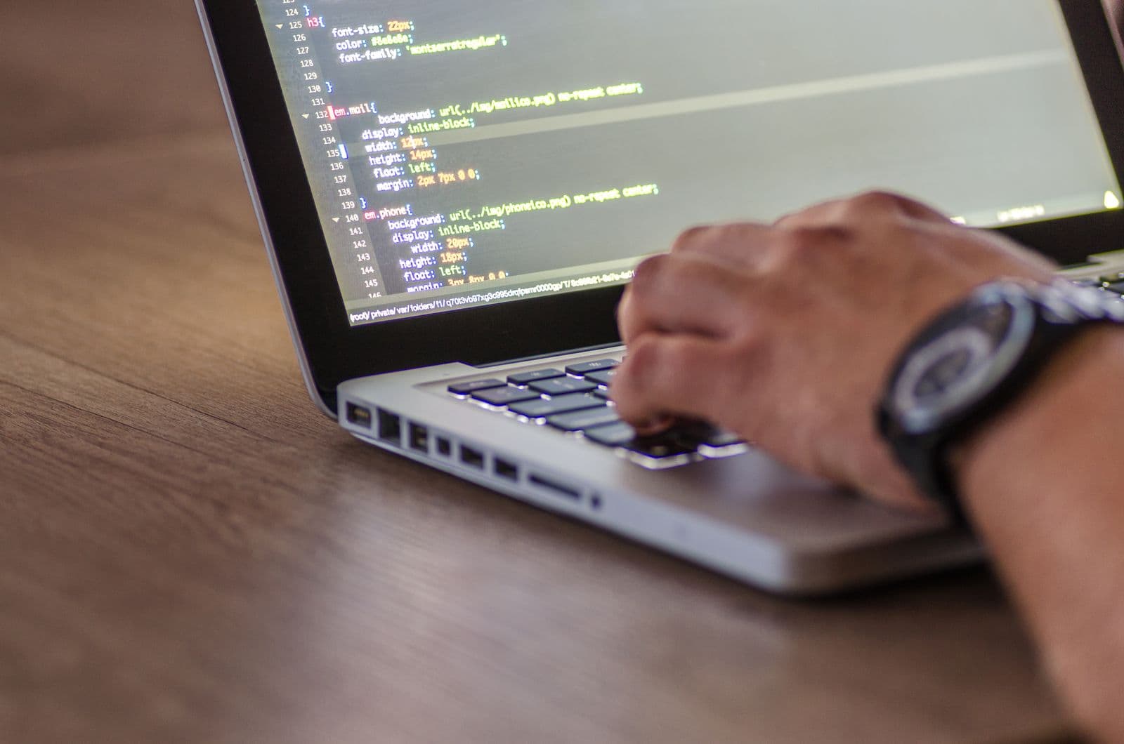 A developer writing front-end code on a laptop, representing a website built for speed, SEO, and conversion